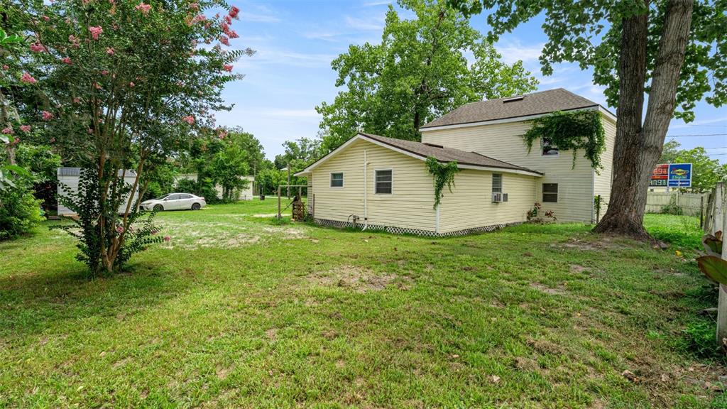 A two-story yellow house with a side addition sits on a grassy lot with trees — 10107 S DIVISION AVENUE, HAMPTON, FL