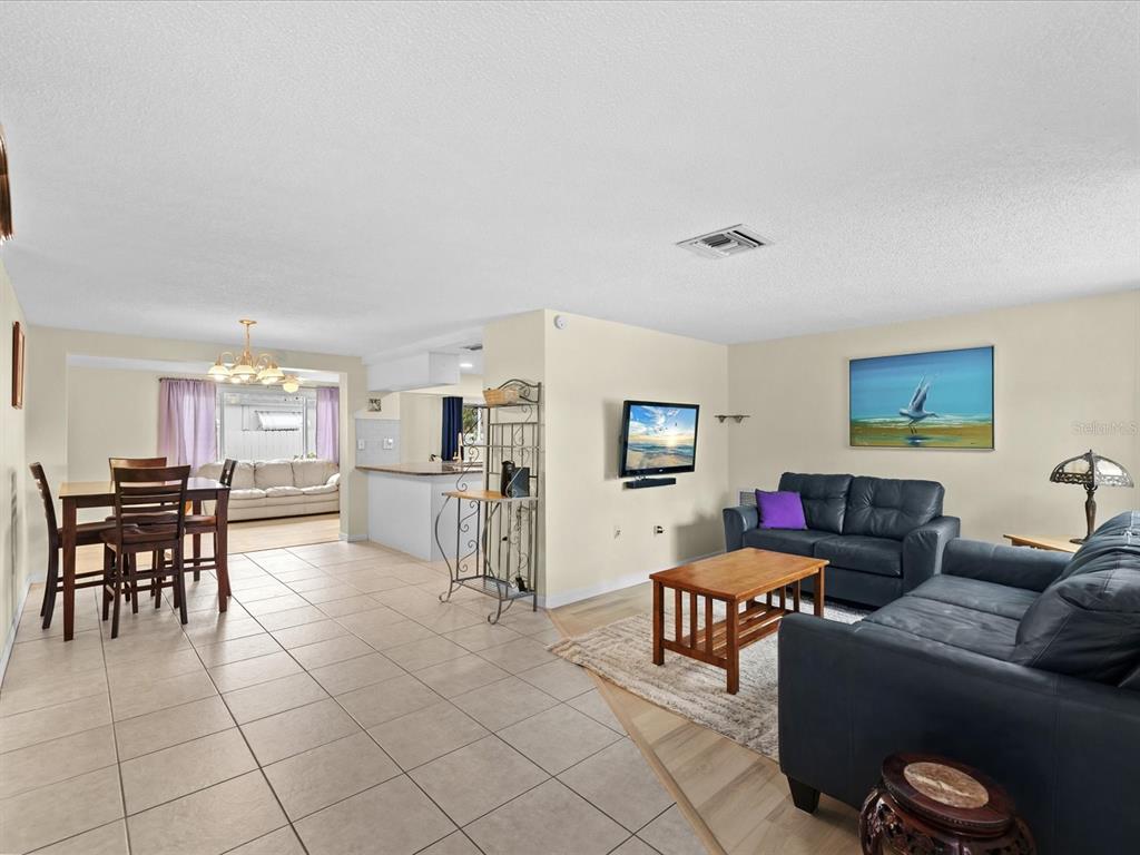 An open-concept living and dining area features tile flooring, dark leather furniture, and neutral walls — 3845 MING TREE DRIVE, NEW PORT RICHEY, FL