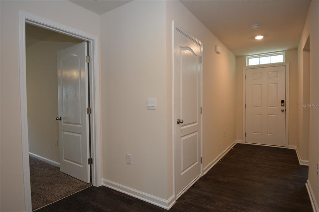 An interior hallway features dark wood-look flooring, two white doors, and a front entry door — 664 GRAND RESERVE DRIVE, BUNNELL, FL