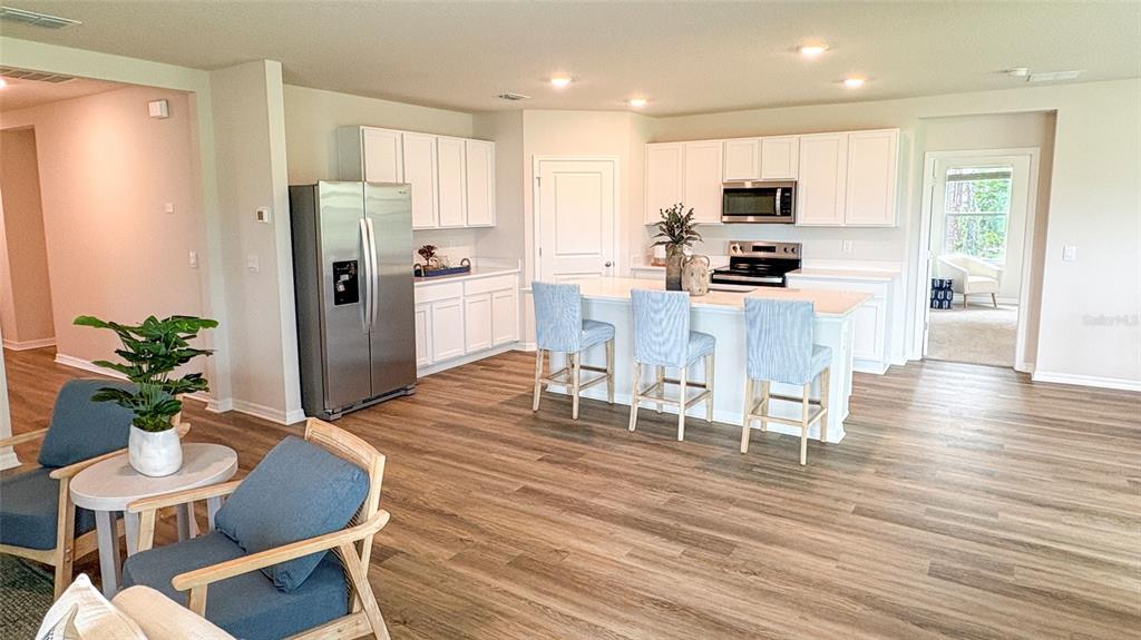 A modern kitchen features white cabinetry, stainless steel appliances, and a central island with seating — 17611 WHISKEY CREEK TRAIL, PARRISH, FL