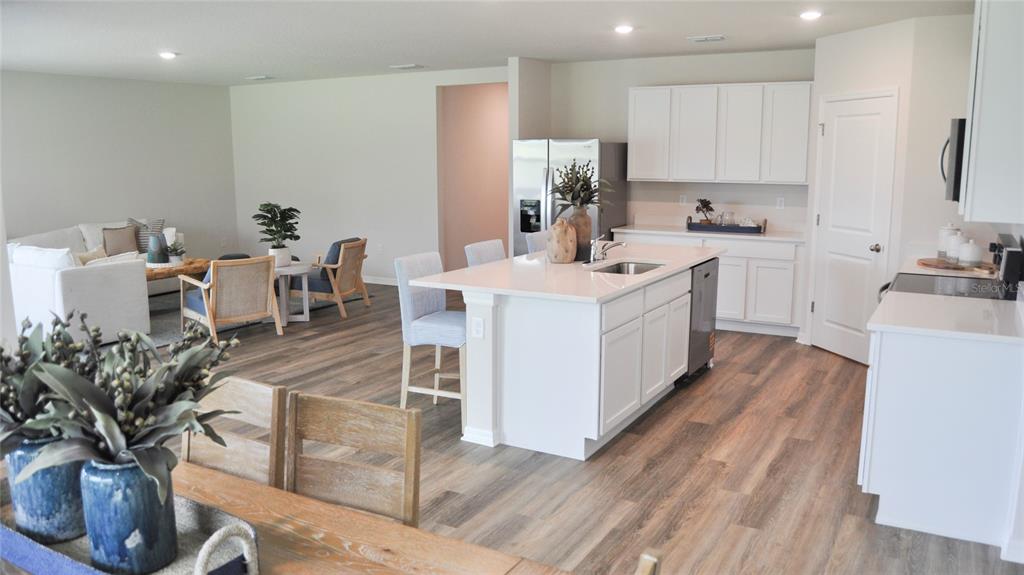 An open-concept kitchen with a white island and cabinetry flows into a living area — 17611 WHISKEY CREEK TRAIL, PARRISH, FL