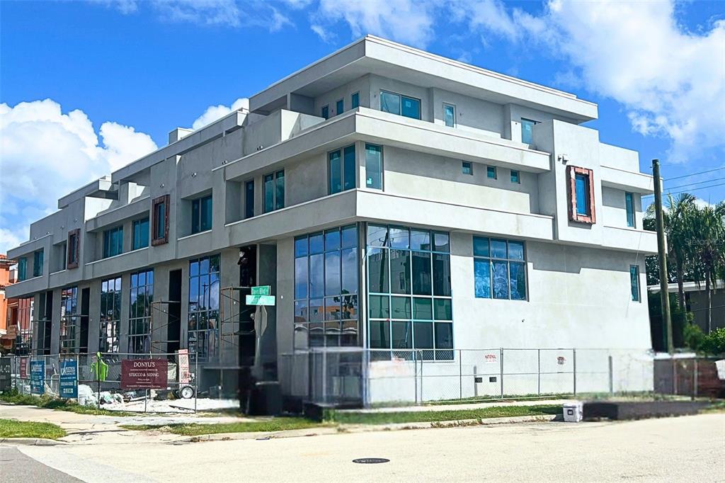 A modern, multi-story building under construction with a gray stucco exterior and large glass windows — 85 DAVIS BOULEVARD UNIT D, TAMPA, FL