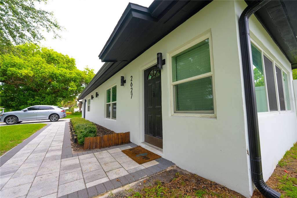 A white house exterior features a black front door, dark trim, and a paved walkway — 2627 AMBERGATE ROAD, WINTER PARK, FL
