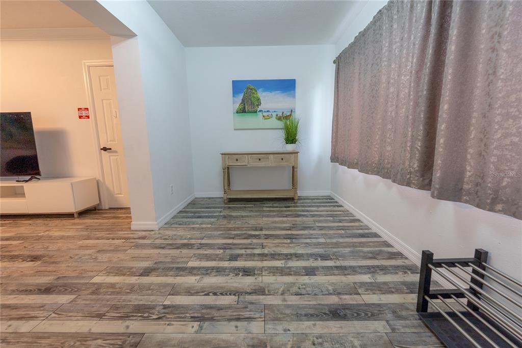 A room with wood-look tile flooring, a console table, wall art, and curtains — 2627 AMBERGATE ROAD, WINTER PARK, FL