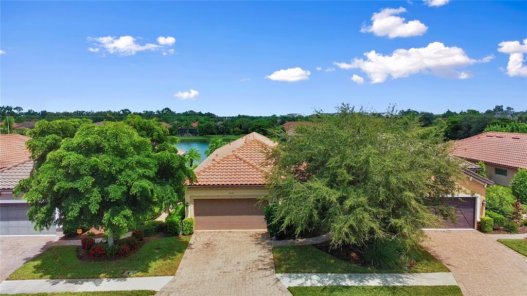 An exterior view of a single-story house with a tiled roof and a paved driveway — 5548 SENTIERO DRIVE, NOKOMIS, FL