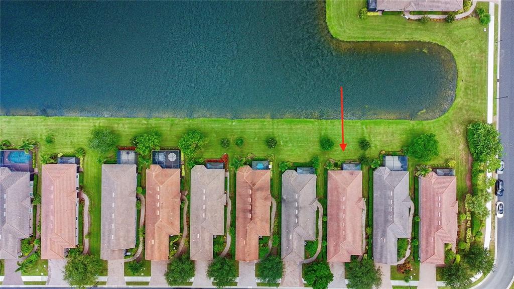 An aerial view shows a row of townhomes with tiled roofs bordering a large lake — 5548 SENTIERO DRIVE, NOKOMIS, FL