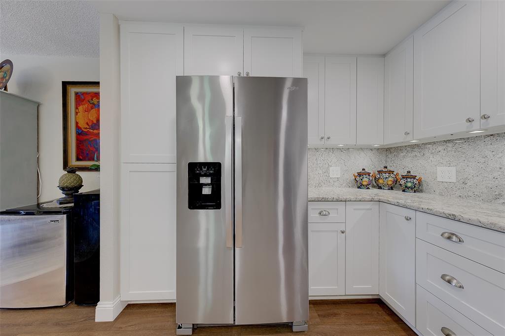 A stainless steel refrigerator stands between white kitchen cabinets and a granite countertop — 1460 GULF BOULEVARD UNIT 305, CLEARWATER, FL
