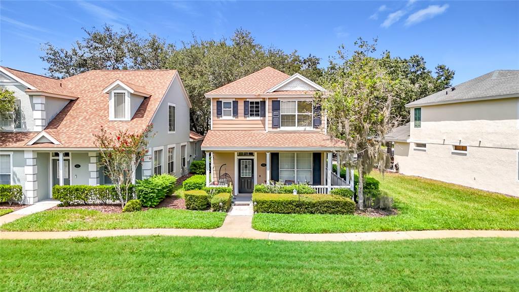 A two-story suburban house with tan siding and a front porch sits between two neighbors — 5014 BRIDGEWAY LANE, LUTZ, FL