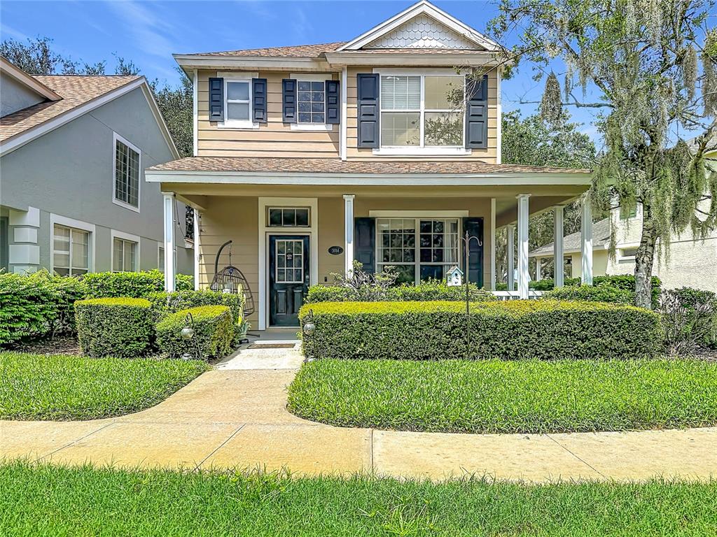 A two-story house with tan siding, a front porch, and a manicured hedge — 5014 BRIDGEWAY LANE, LUTZ, FL