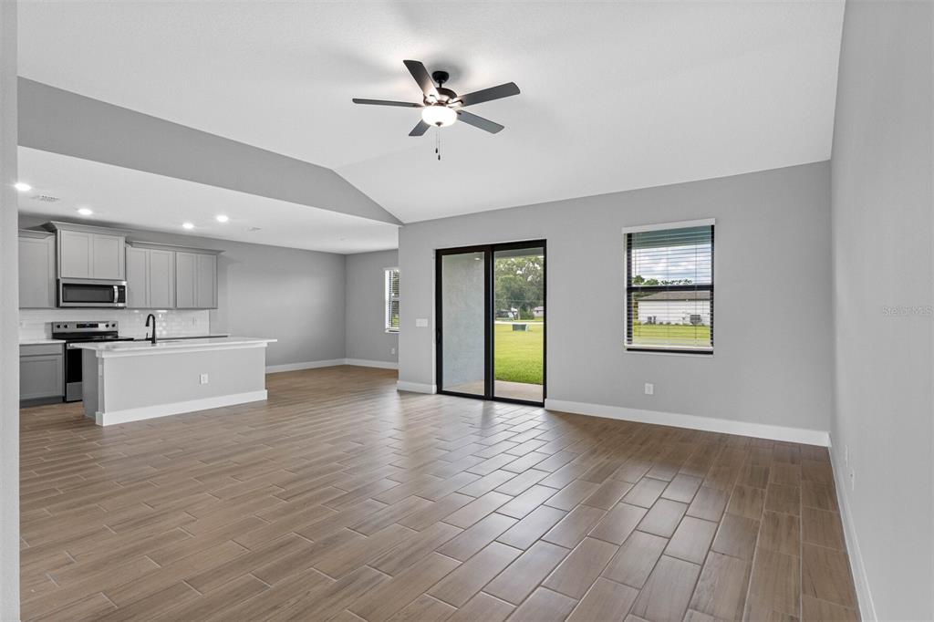 An open-concept living area features wood-look tile flooring, a ceiling fan, and a kitchen — 13521 WALDEN SHEFFIELD ROAD, DOVER, FL