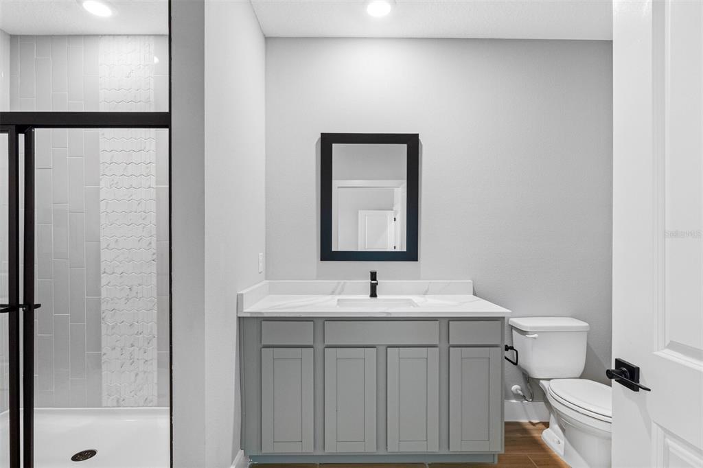 A bathroom features a gray vanity with a white countertop, a mirror, and a shower — 13521 WALDEN SHEFFIELD ROAD, DOVER, FL