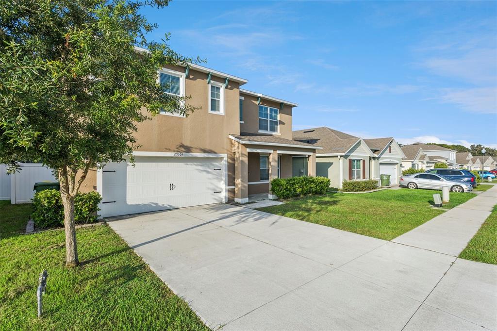 A two-story suburban house with a tan stucco exterior, a white garage, and a driveway — 29505 CASPIAN STREET, LEESBURG, FL