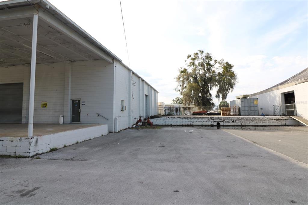 An exterior view of a warehouse building with a loading dock and paved parking area — 210 NW 13TH STREET, OCALA, FL