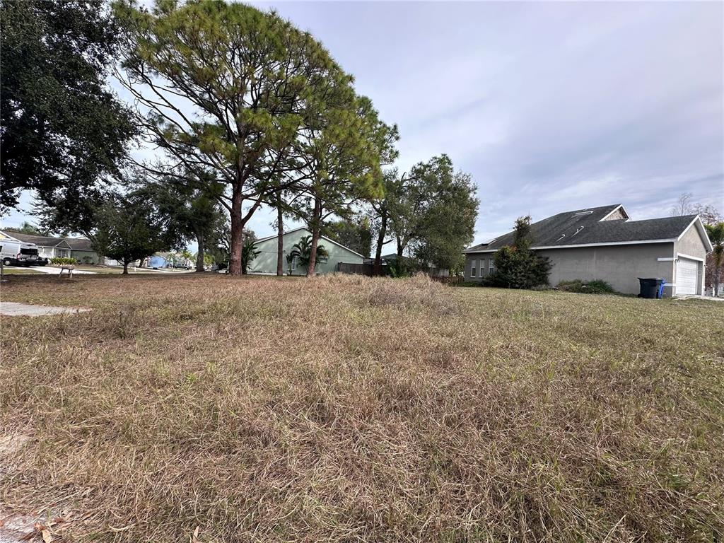 A vacant, grassy residential lot sits between two houses under a cloudy sky — 236 LOOKOUT DRIVE, APOLLO BEACH, FL