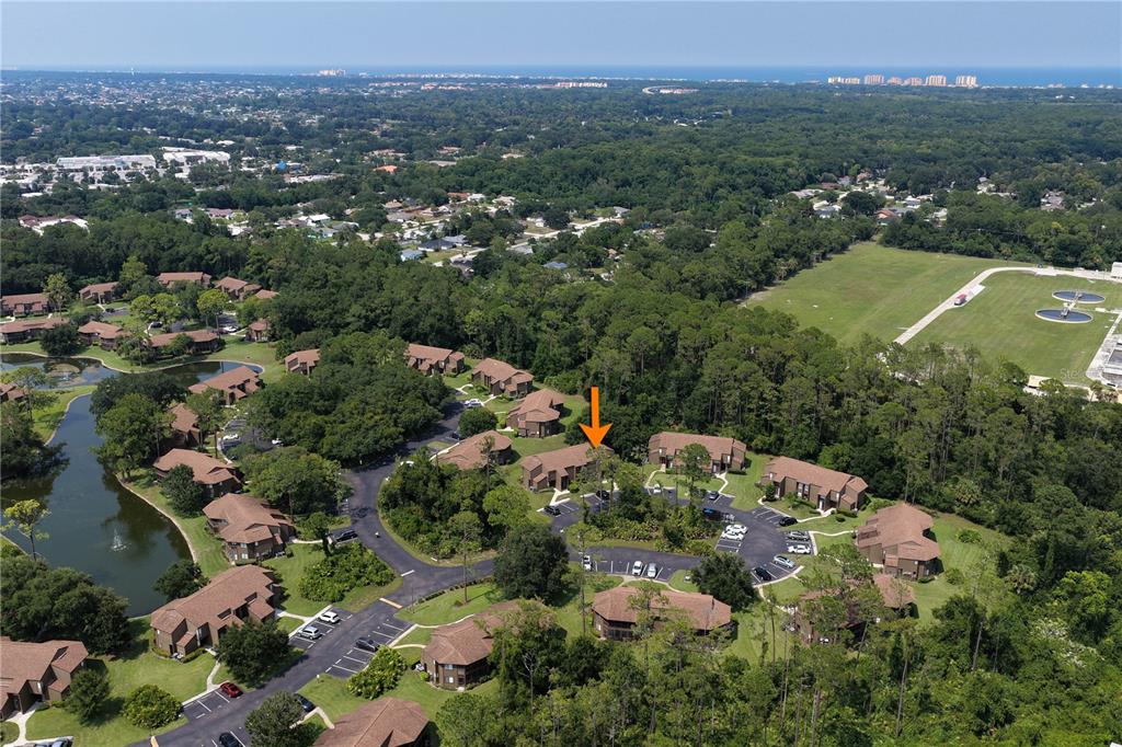 An aerial view shows a multi-unit residential complex surrounded by trees and a small pond — 37 HEMBURY LANE, PALM COAST, FL