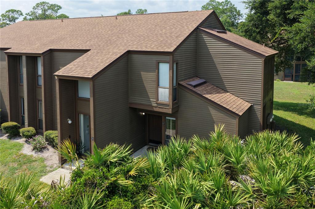 An exterior view of a two-story brown wood-sided townhouse with a shingled roof — 37 HEMBURY LANE, PALM COAST, FL
