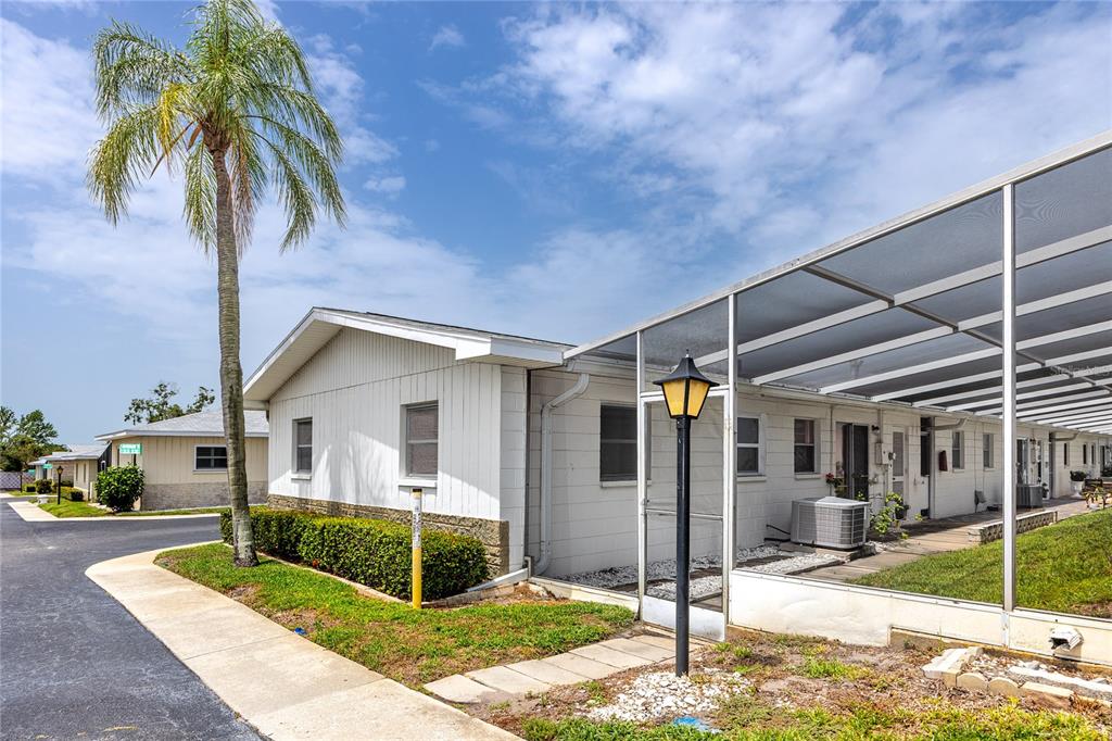 A street view of single-story residential buildings with white siding and a palm tree — 12400 PARK BOULEVARD UNIT 417, SEMINOLE, FL