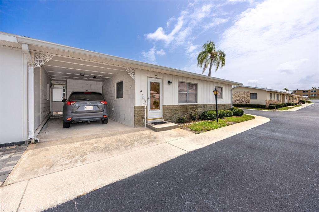A white single-story building with a screened-in patio and a tall palm tree outside — 12400 PARK BOULEVARD UNIT 417, SEMINOLE, FL