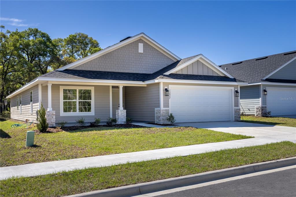 A single-story suburban house with gray siding, a two-car garage, and a covered porch — 16929 NW 176TH WAY, ALACHUA, FL