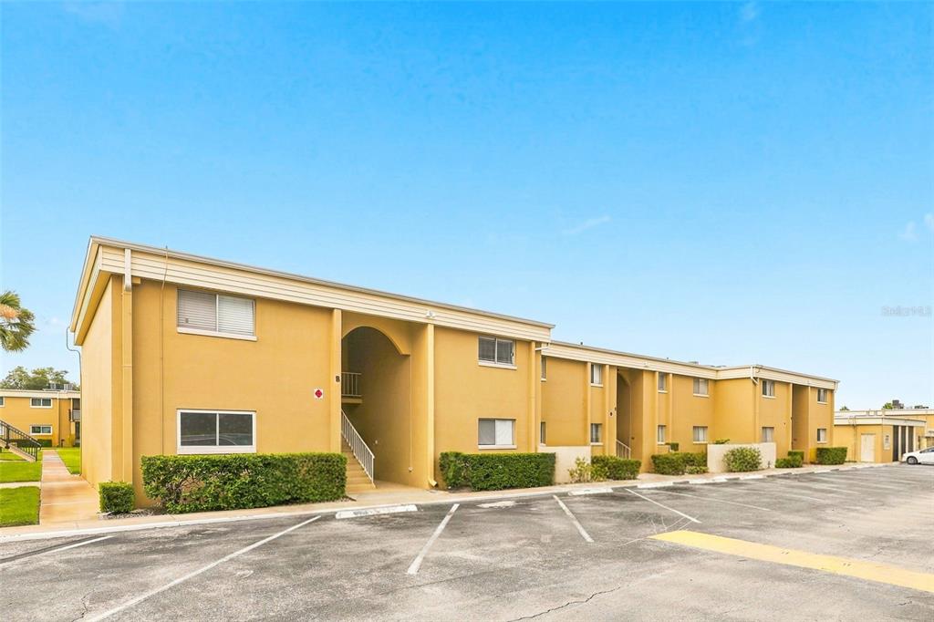 A two-story yellow apartment building with a parking lot in the foreground — 1000 LAKE OF THE WOODS BOULEVARD UNIT B202, FERN PARK, FL