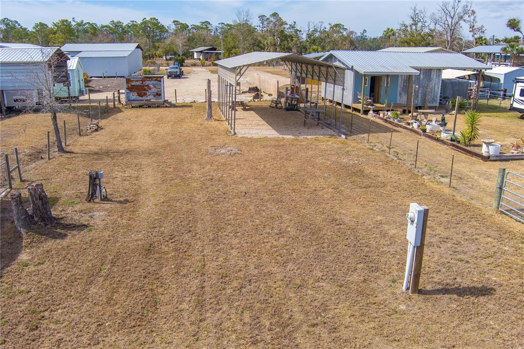 An aerial view shows a grassy yard with a metal carport and a small house — 507 4TH STREET NW, STEINHATCHEE, FL