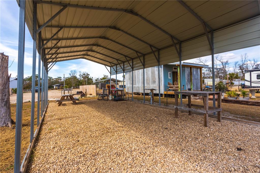 A large metal carport covers a gravel area with a wooden table and chairs — 507 4TH STREET NW, STEINHATCHEE, FL