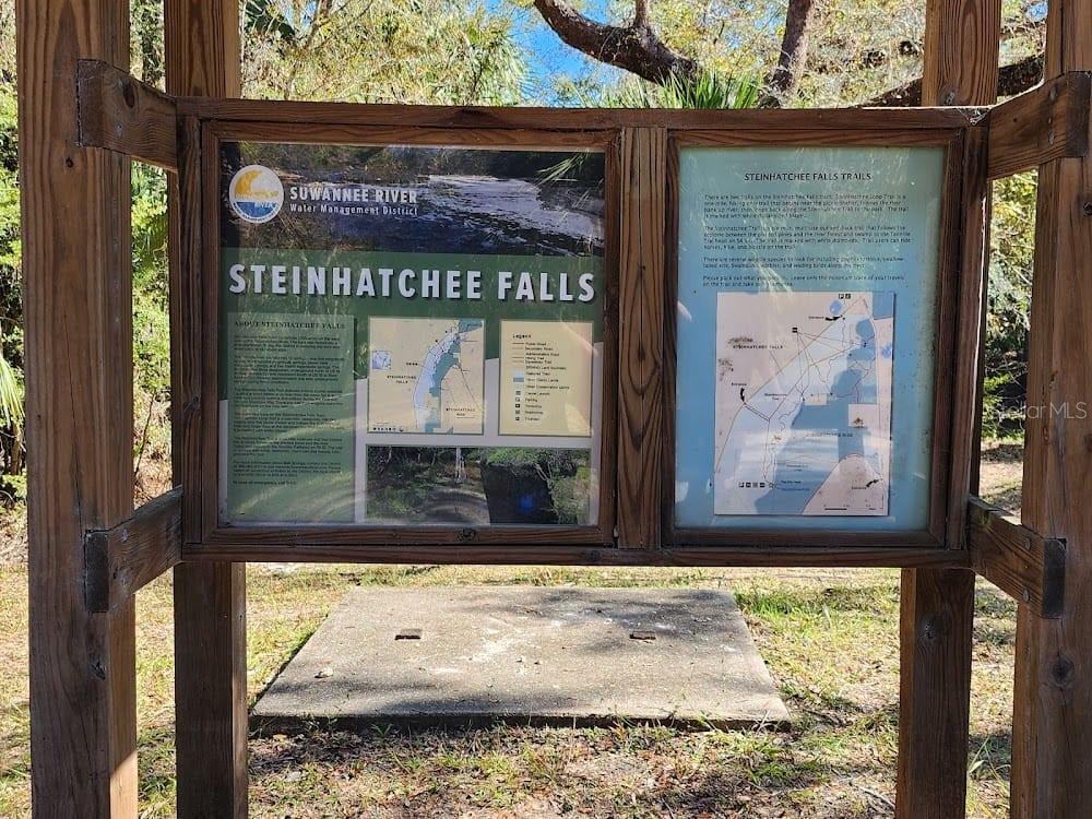 A wooden information kiosk stands outdoors displaying maps and details about Steinhatchee Falls trails — 507 4TH STREET NW, STEINHATCHEE, FL