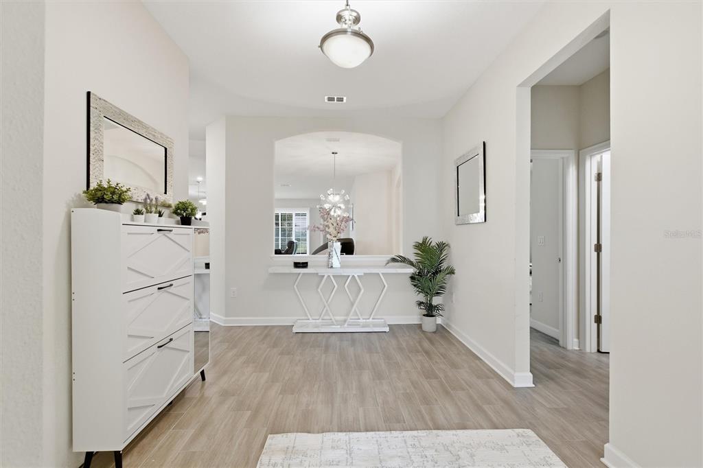 A bright entryway features light wood-look flooring, a white console table, and a shoe cabinet — 1077 DOWNSWING PL, DAVENPORT, FL