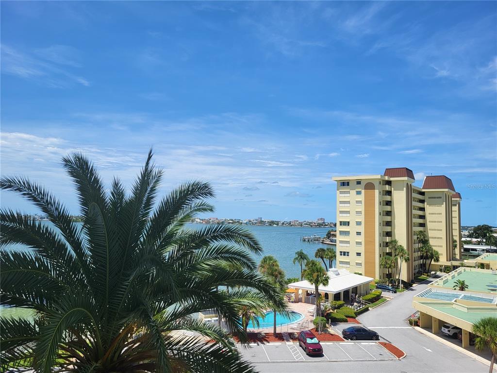 A view from a balcony overlooking a swimming pool, parking lot, and a large bay — 4775 COVE CIRCLE UNIT 606, ST PETERSBURG, FL