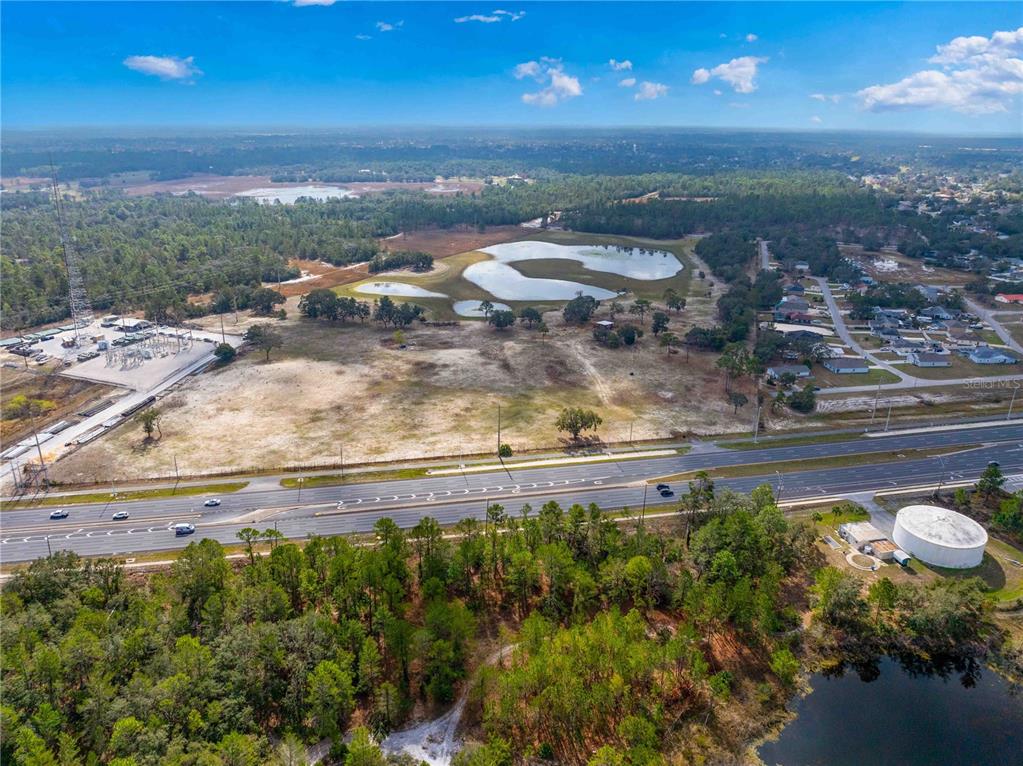 An aerial view shows a large, undeveloped plot of land next to a multi-lane highway — 10300 CORTEZ BOULEVARD, BROOKSVILLE, FL