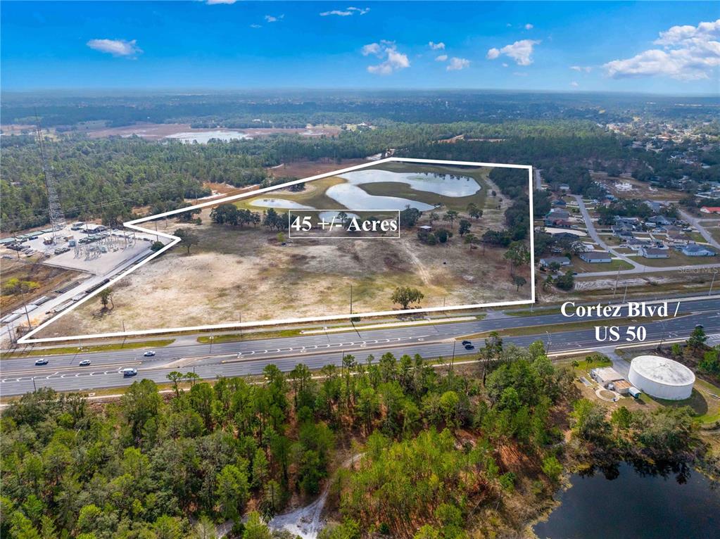 An aerial view shows a large, undeveloped 45-acre plot of land bordering a highway — 10300 CORTEZ BOULEVARD, BROOKSVILLE, FL