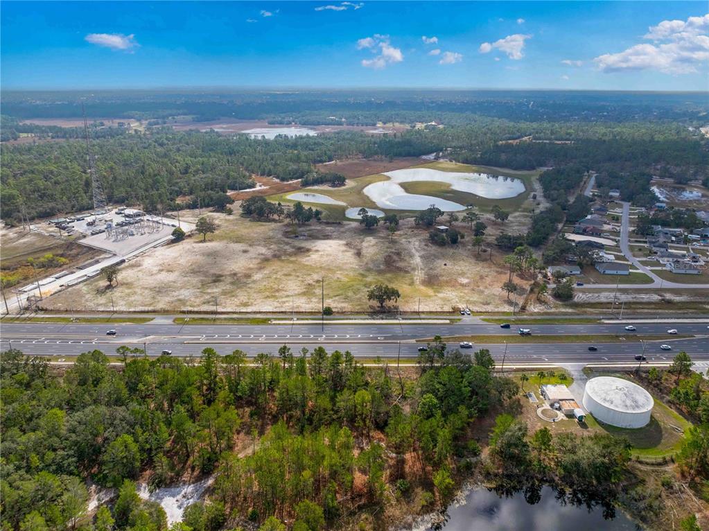An aerial view shows a large vacant lot next to a highway and utility substation — 10300 CORTEZ BOULEVARD, BROOKSVILLE, FL
