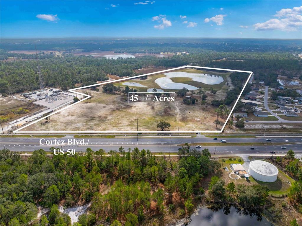 An aerial view shows a large, undeveloped parcel of land bordering a highway — 10300 CORTEZ BOULEVARD, BROOKSVILLE, FL