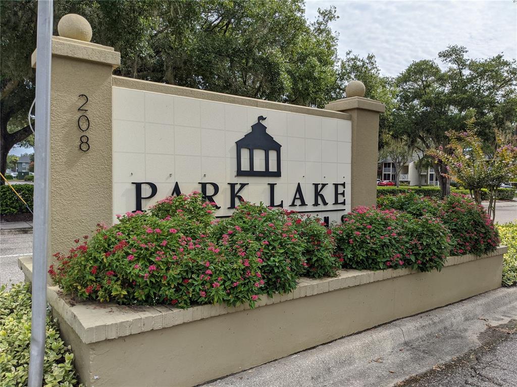 A beige monument sign for Park Lake sits behind a planter filled with pink flowers — 209 LAKE BROOK CIRCLE UNIT 103, BRANDON, FL