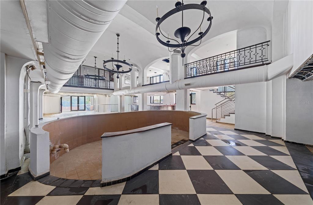A large, open-concept room features a curved tiled bar, checkered flooring, and two hanging chandeliers — 201-202 TIZOL STREET, SAN JUAN, PR