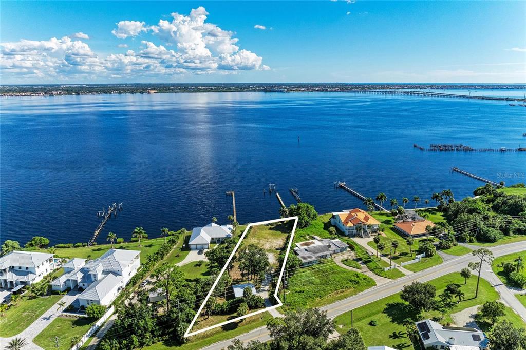 An aerial view shows a waterfront lot outlined in white next to several houses — 24181 HARBORVIEW ROAD, PUNTA GORDA, FL