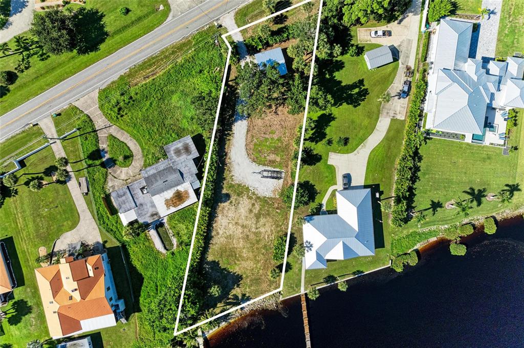 An aerial view shows a vacant, narrow rectangular lot situated between two residential properties — 24181 HARBORVIEW ROAD, PUNTA GORDA, FL