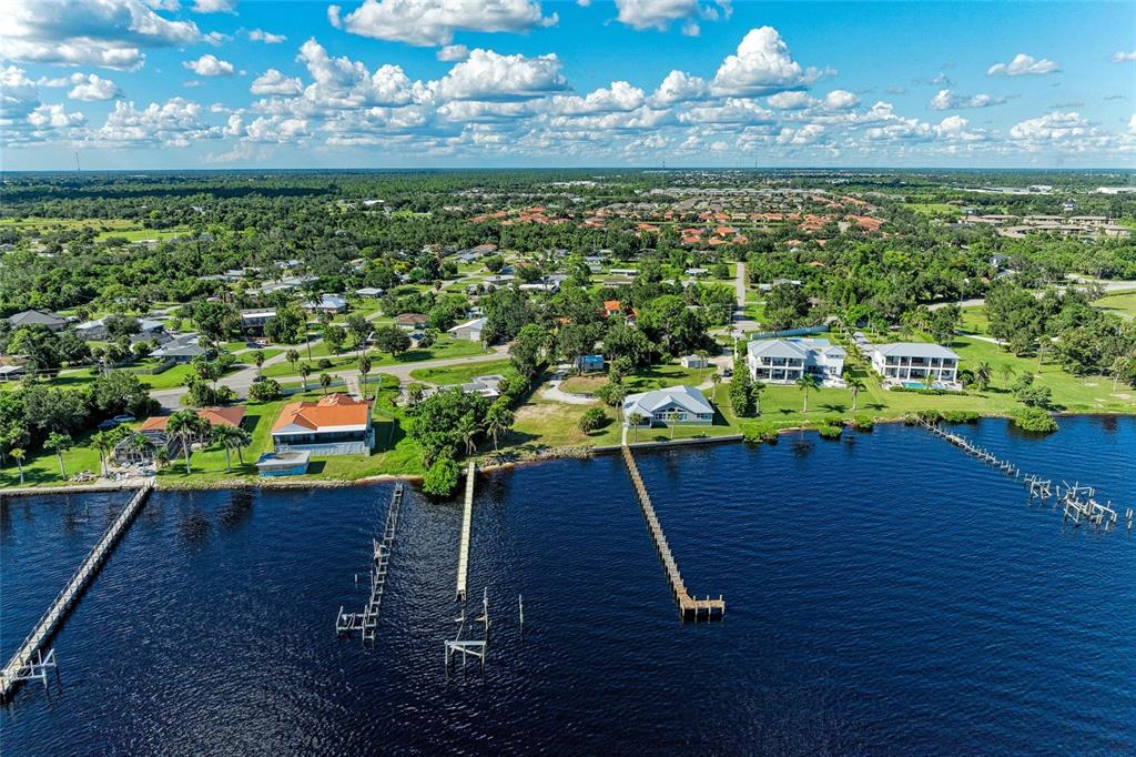 An aerial view shows several waterfront houses with private docks extending into a large lake — 24181 HARBORVIEW ROAD, PUNTA GORDA, FL