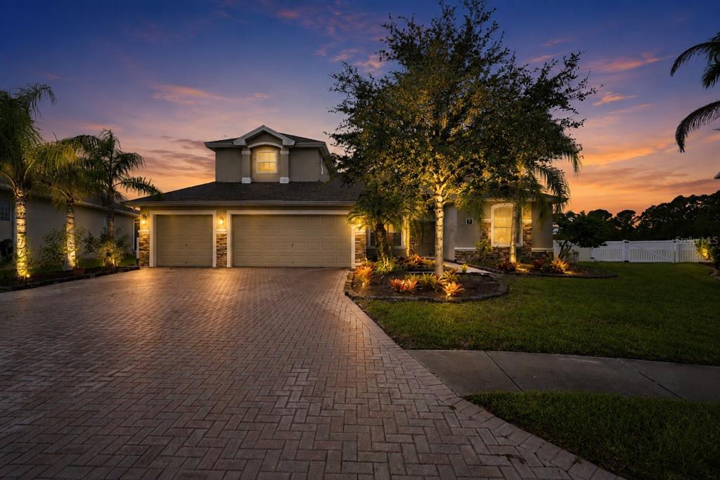 A two-story house with a paved driveway and landscape lighting at sunset — 197 BRANDY CREEK CIRCLE SE, PALM BAY, FL
