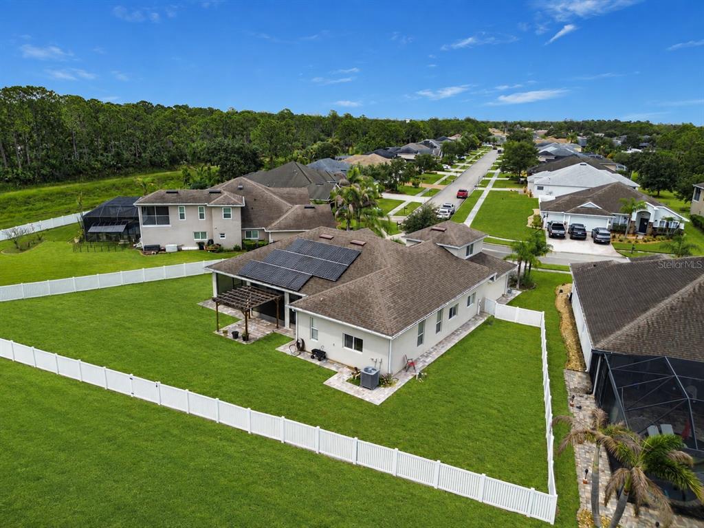 An aerial view shows a suburban house with solar panels, a fenced yard, and patio — 197 BRANDY CREEK CIRCLE SE, PALM BAY, FL