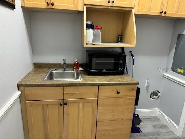 A laundry room features light wood cabinets, a stainless steel sink, and a black microwave — 27551 CASHFORD CIRCLE UNIT 101, WESLEY CHAPEL, FL