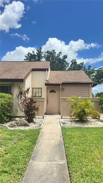 A tan one-story townhouse with a brown shingled roof and a concrete walkway leading to the entrance — 5736 BEAUMONT LOOP, NORTH PORT, FL