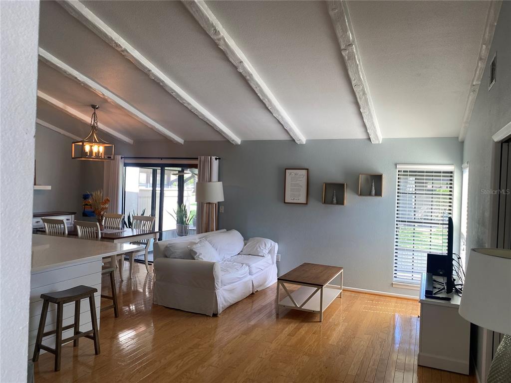 A living room with hardwood floors, white exposed ceiling beams, and a white sofa — 5736 BEAUMONT LOOP, NORTH PORT, FL