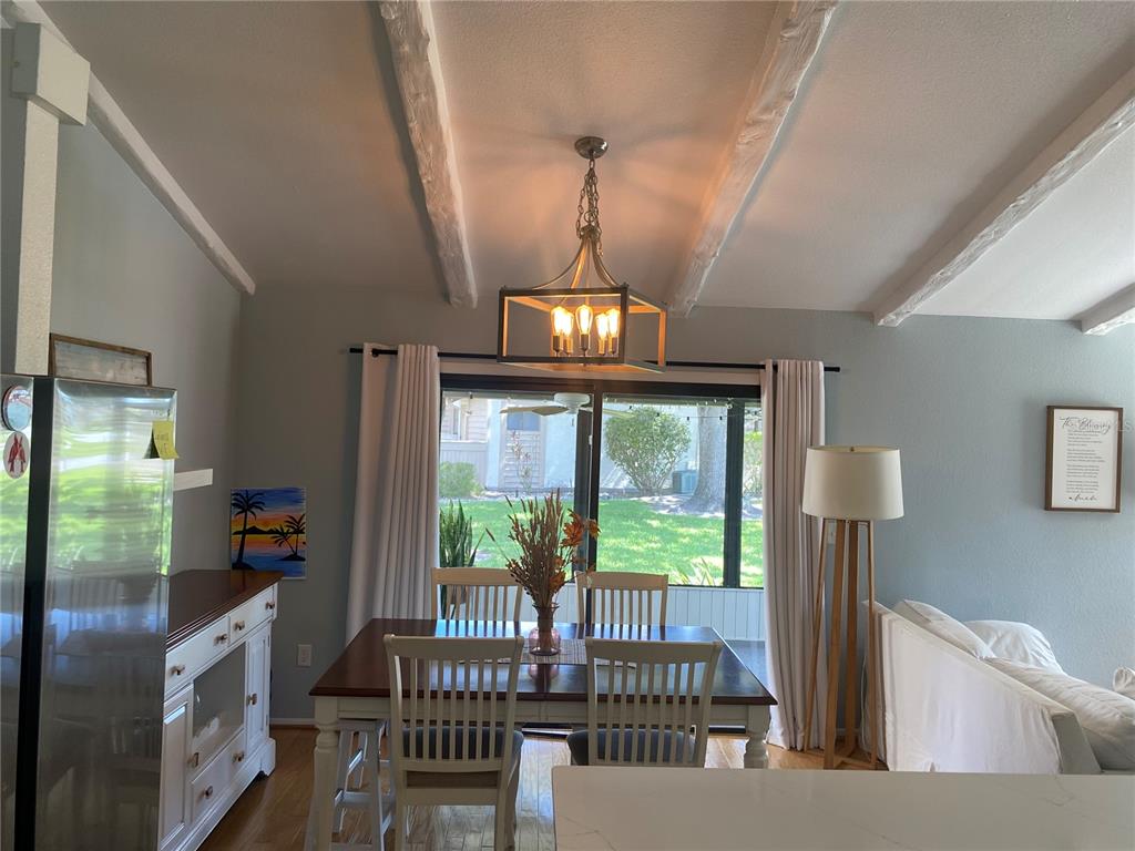 A dining area with a wooden table, four chairs, a chandelier, and sliding glass doors — 5736 BEAUMONT LOOP, NORTH PORT, FL