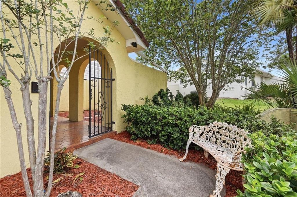A yellow single-story house with a tile roof, two-car garage, and an American flag — 7026 WILLOW RUN LOOP, LAKELAND, FL