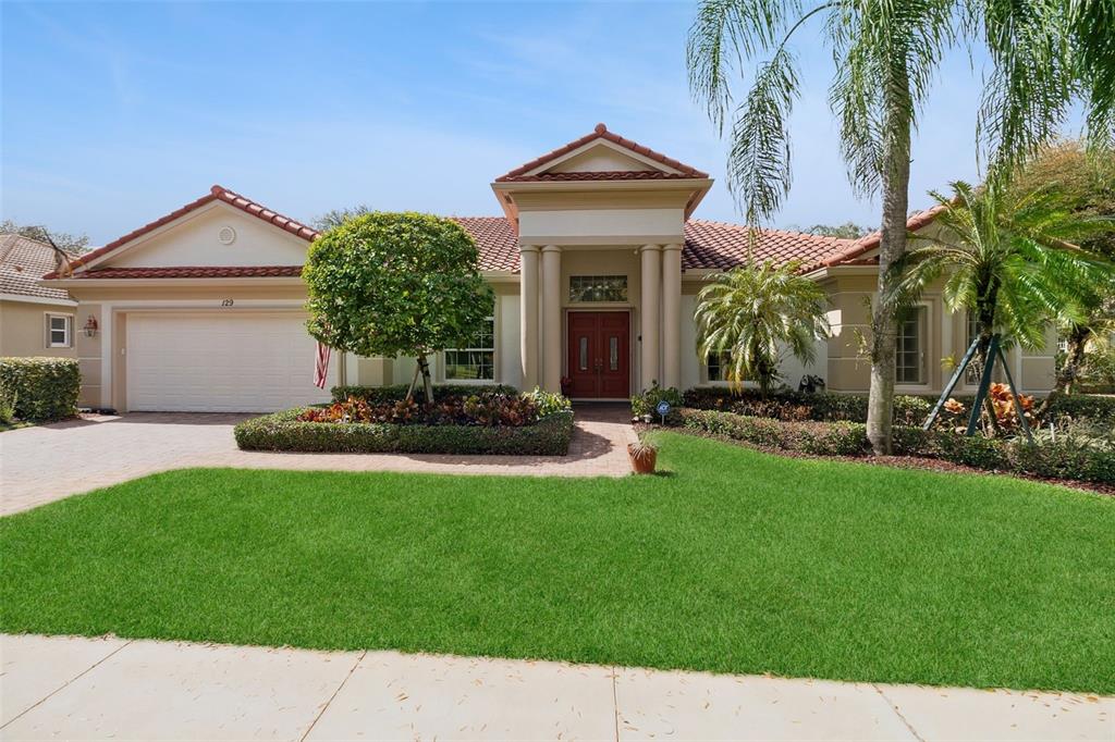 A single-story house with a red tile roof, beige stucco walls, and a two-car garage — 129 MYSTIC LANE, JUPITER, FL