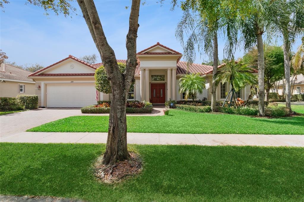A single-story house with a red tile roof, white garage, and a central columned entrance — 129 MYSTIC LANE, JUPITER, FL