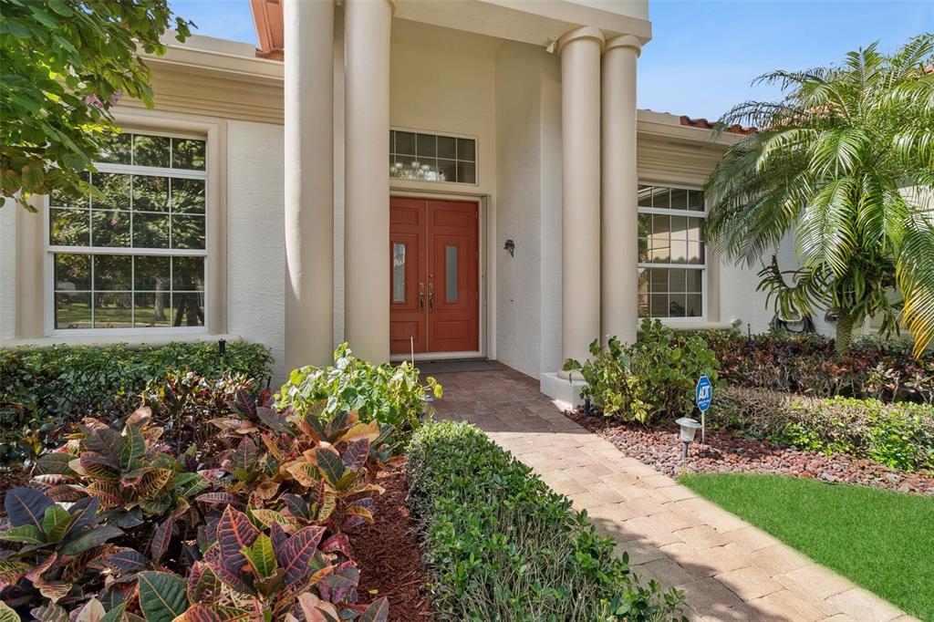 A front entrance with a red double door, white columns, and a paved walkway — 129 MYSTIC LANE, JUPITER, FL