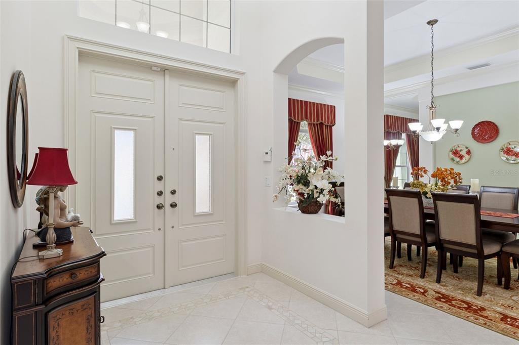 An entryway with double doors, tile floors, and an arched opening into a dining room — 129 MYSTIC LANE, JUPITER, FL