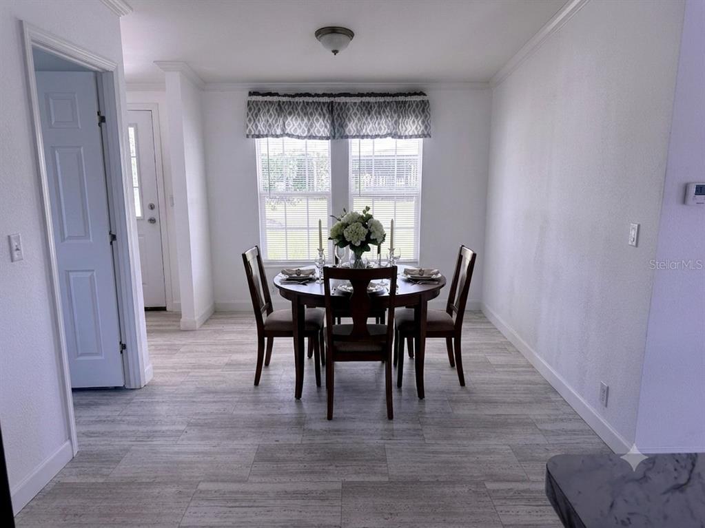 An empty room features light gray walls, dark wood-look flooring, and two windows with valances — 3496 GREENBLUFF ROAD UNIT 1118, ZELLWOOD, FL